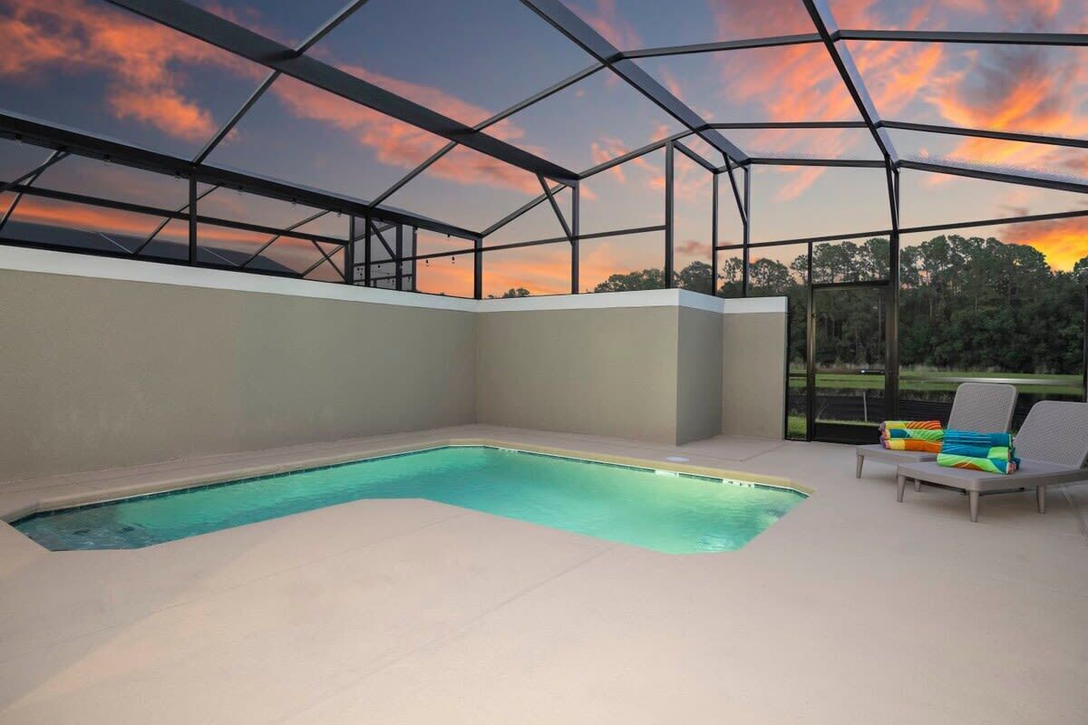 A modern indoor pool area with a glass ceiling, a pool, and lounge chairs.