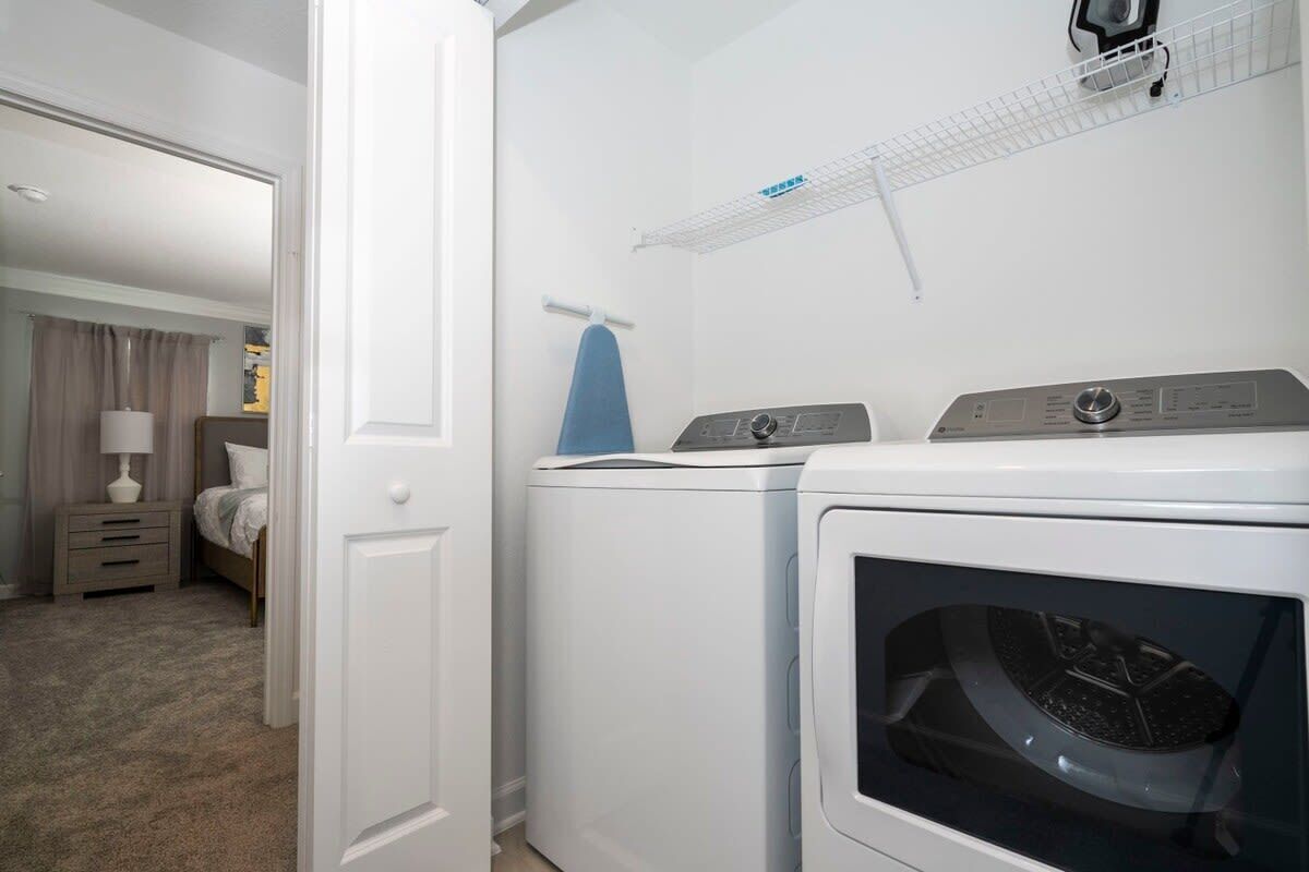 A laundry room with two washing machines and a drying rack.