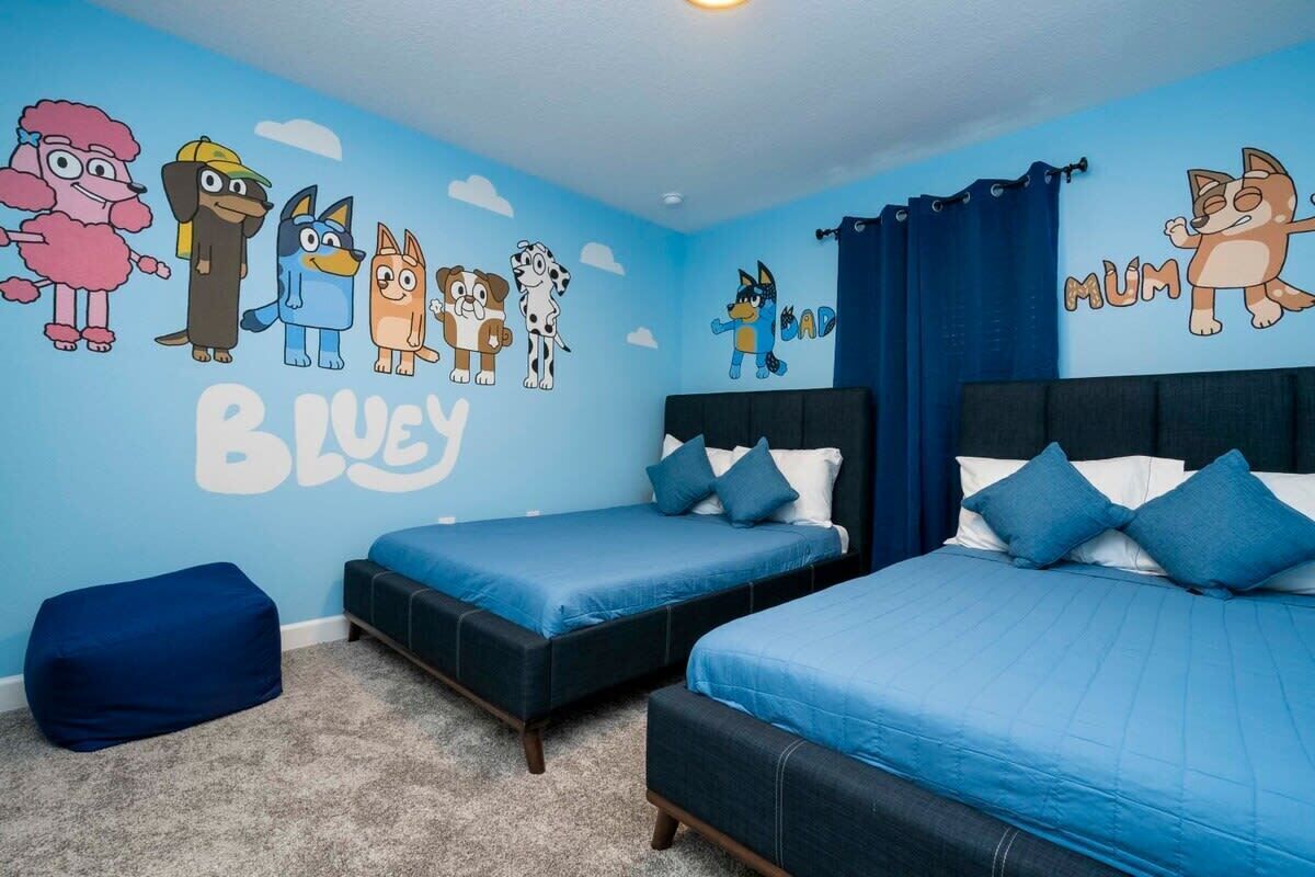 A bedroom with two beds, a blue wall, and cartoon animal decals.