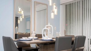 A modern dining area with a wooden table, four grey chairs, and pendant lights. - Marvelous 4Bd with Pool at Storey Lake Resort 2601 (Kissimmee)
