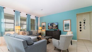 Een woonkamer met een bank, fauteuil, salontafel en televisie.