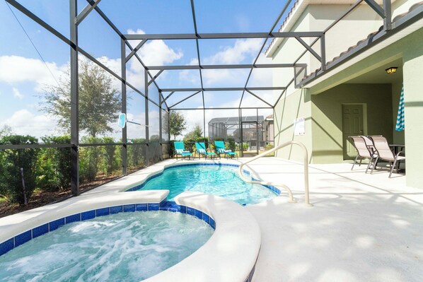 Ein Poolbereich mit Whirlpool, Liegestühlen und einer überdachten Terrasse.