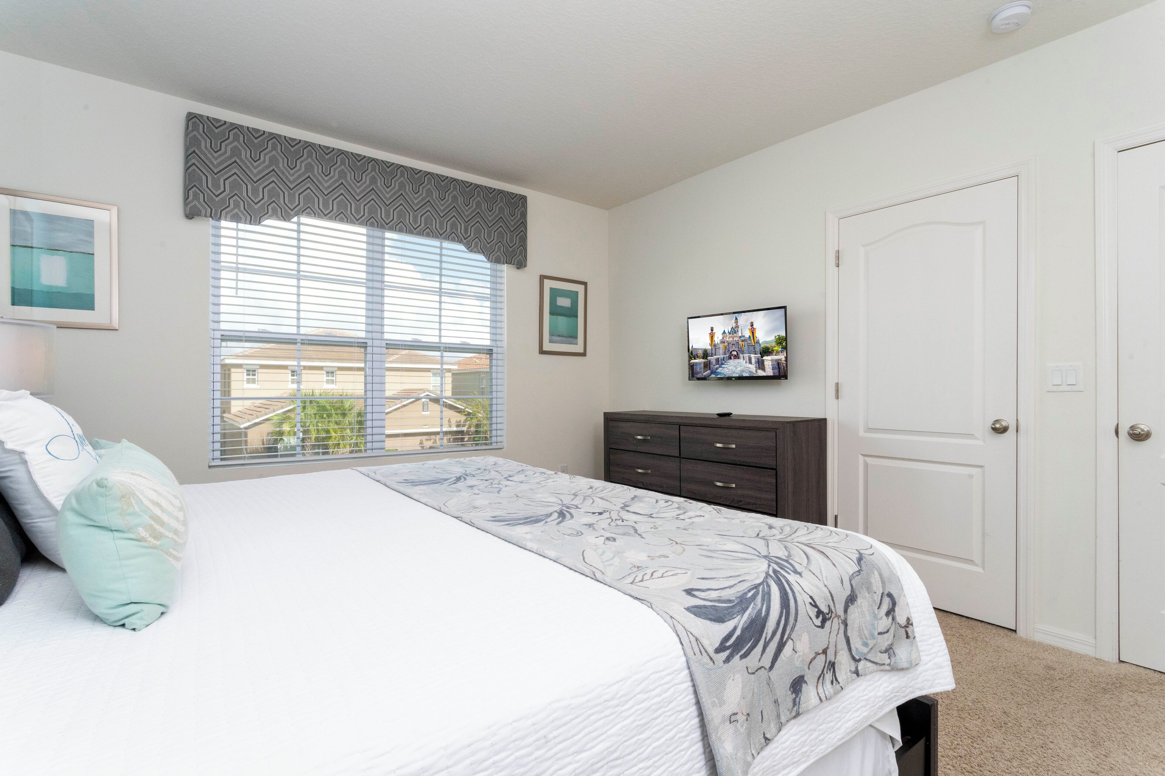 A bedroom with a bed, a dresser, a television, and a door.