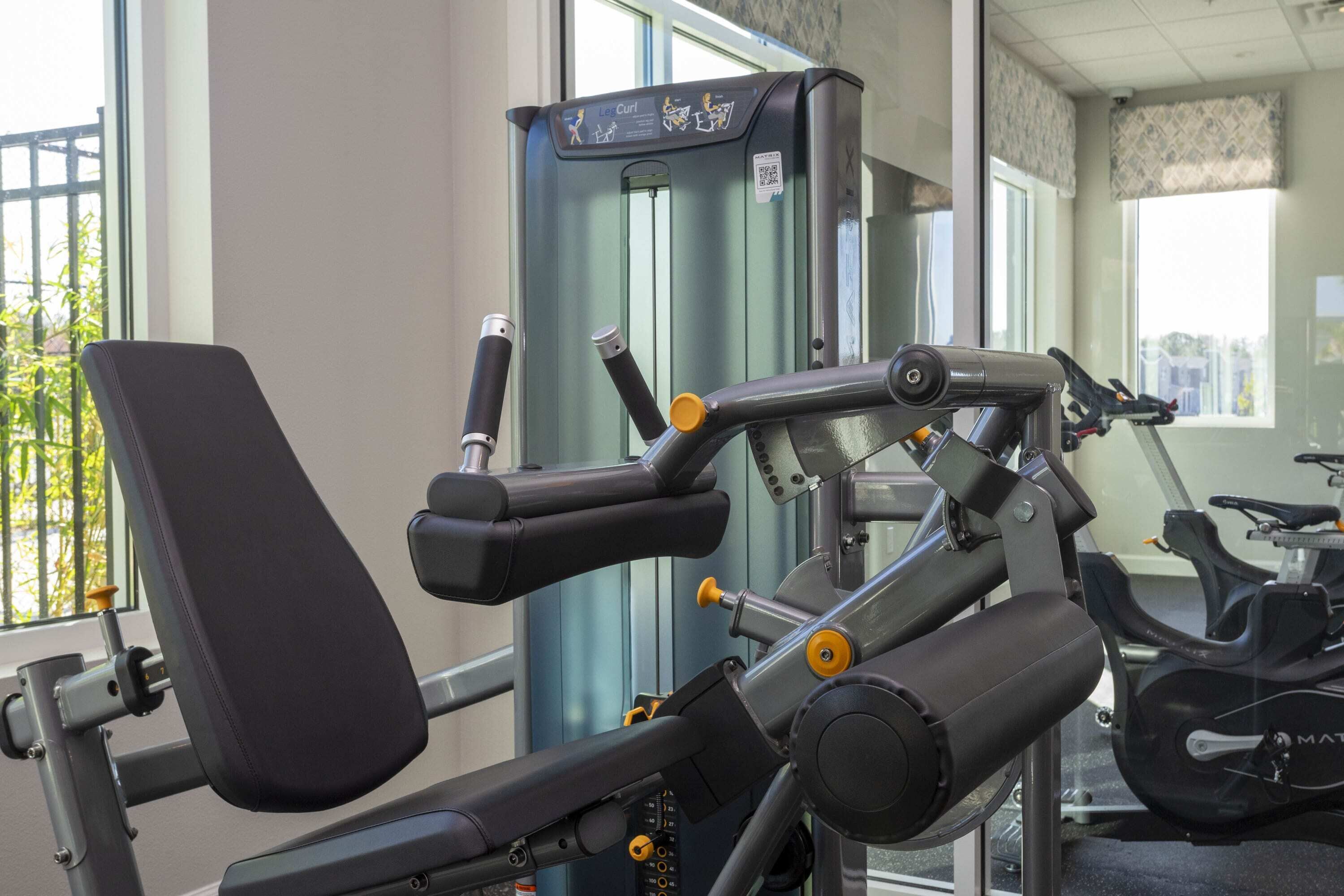 A gym with exercise equipment, large windows, and a view of the outside.