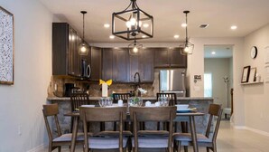 A modern kitchen with dark cabinets, a central island with seating, pendant lighting, and stainless steel appliances. - Stunning 3Bd Close to Disney at Fiesta Key 4764 (Kissimmee)