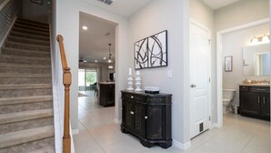 A modern interior with a staircase, a dark wooden cabinet, and a white door. - Stunning 3Bd Close to Disney at Fiesta Key 4764 (Kissimmee)