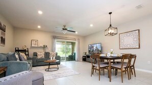 A modern living room with a sofa, coffee table, and dining table set for four. - Stunning 3Bd Close to Disney at Fiesta Key 4764 (Kissimmee)