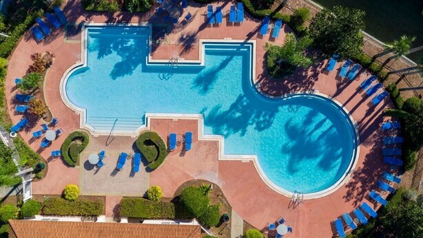 An aerial view of a resort with a large central pool, multiple sun loungers, and surrounding greenery. - Stunning 3Bd Close to Disney at Fiesta Key 4764 (Kissimmee)