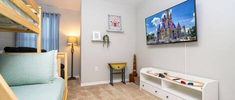A child's room with bunk beds, a TV, a play mat, and a castle-themed picture.