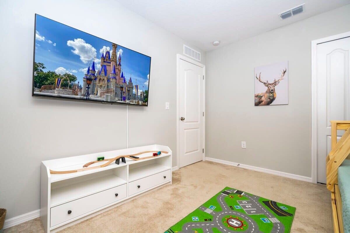 Une chambre d’enfant avec un décor mural sur le thème d’un château, une image de cerf, un tapis de jeu et un meuble de rangement blanc.