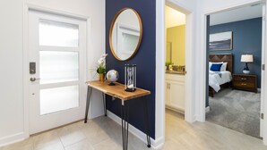 A hotel room with a wooden console table, a round mirror, a globe, and a small plant. - Stunning 4 Bd w/ Pool Close to Disney at Champions Gate 1158 (Davenport)