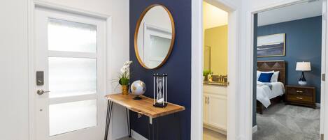 Une chambre d’hôtel avec une console en bois, un miroir rond, un globe terrestre et une petite plante.