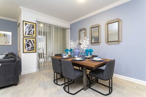 Un comedor con una mesa de madera, sillas grises y jarrones decorativos.