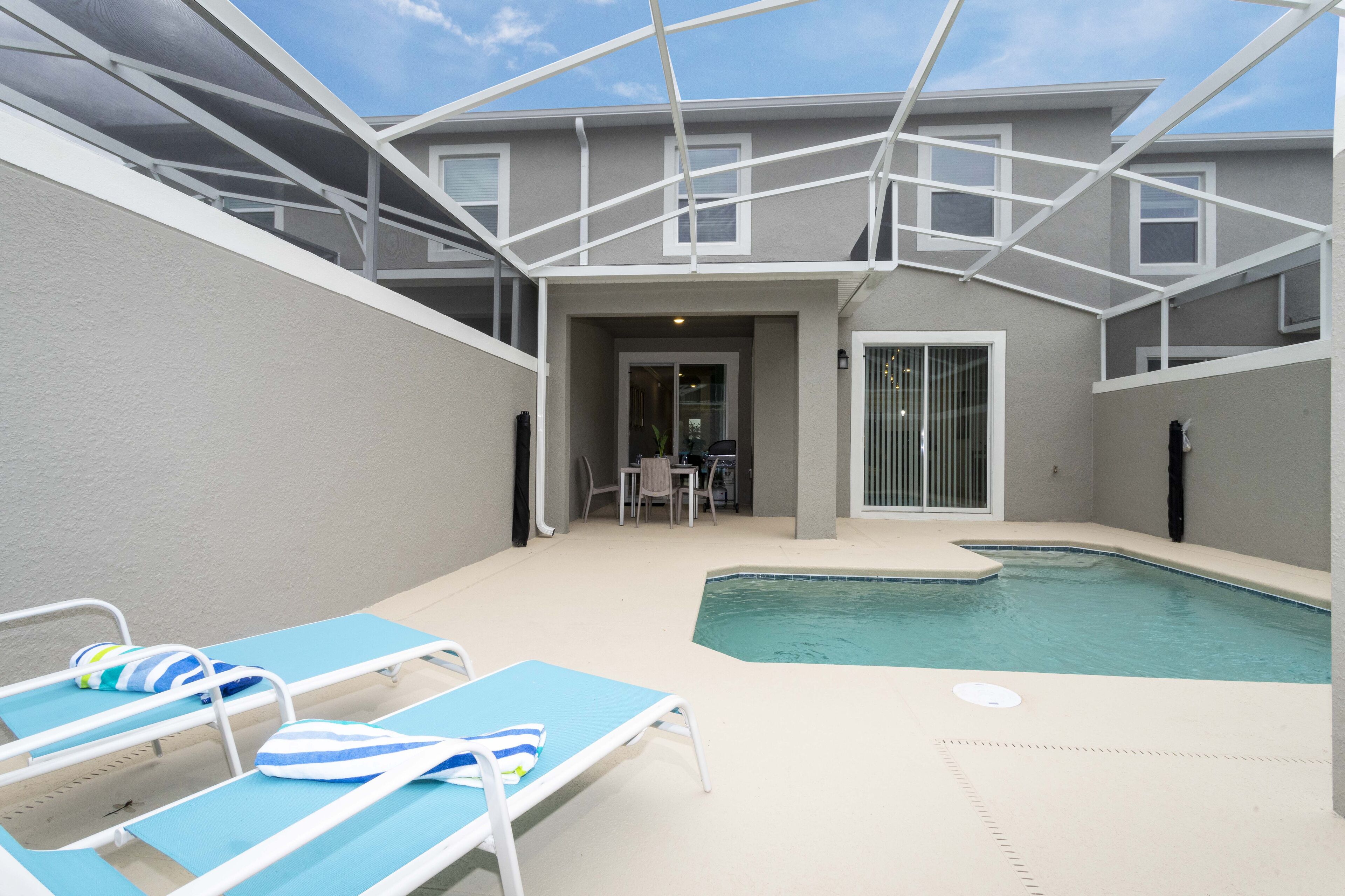 An outdoor swimming pool area with lounge chairs and a covered patio.