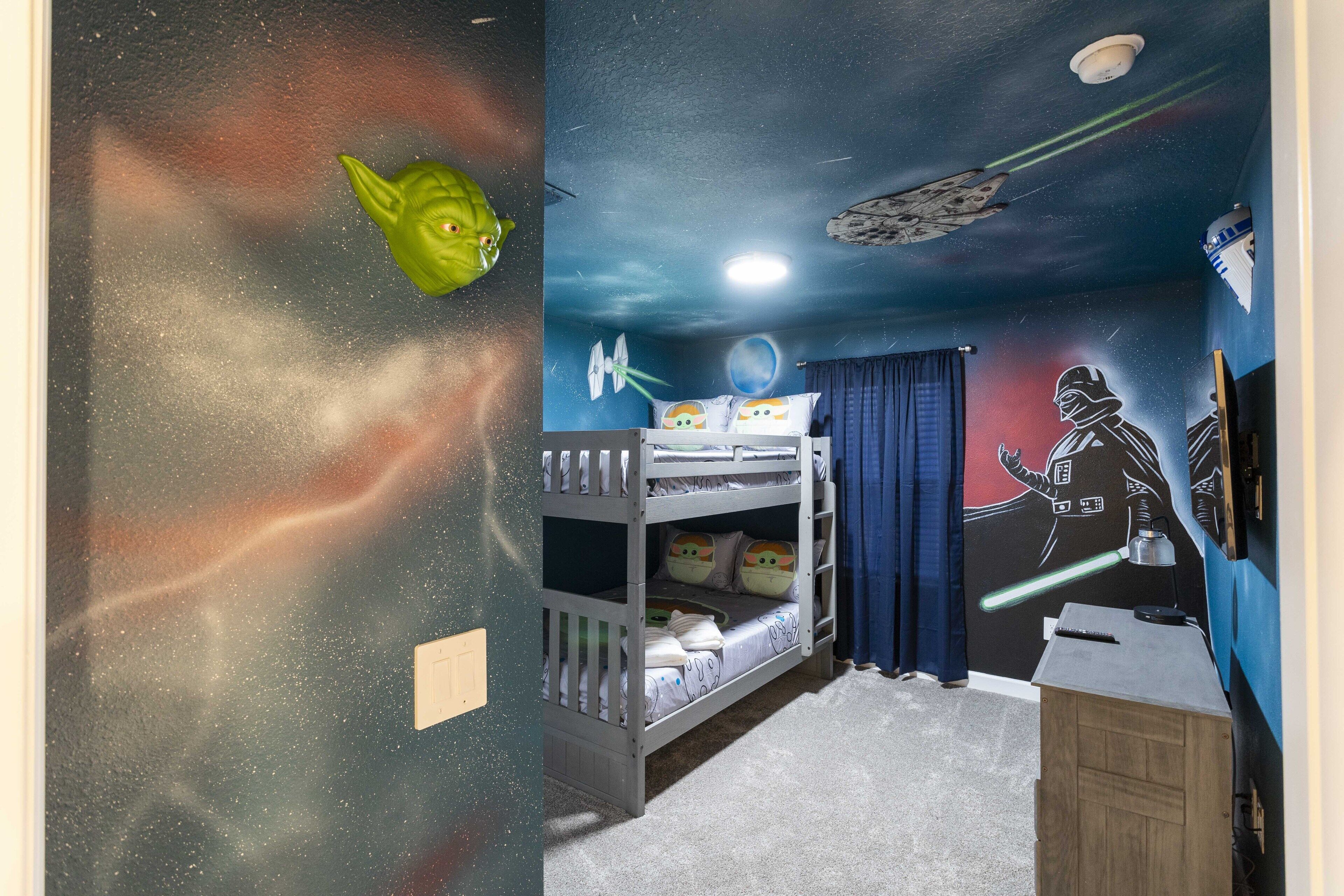 A child's bedroom with bunk beds, a Star Wars mural, and a galaxy-themed wall.