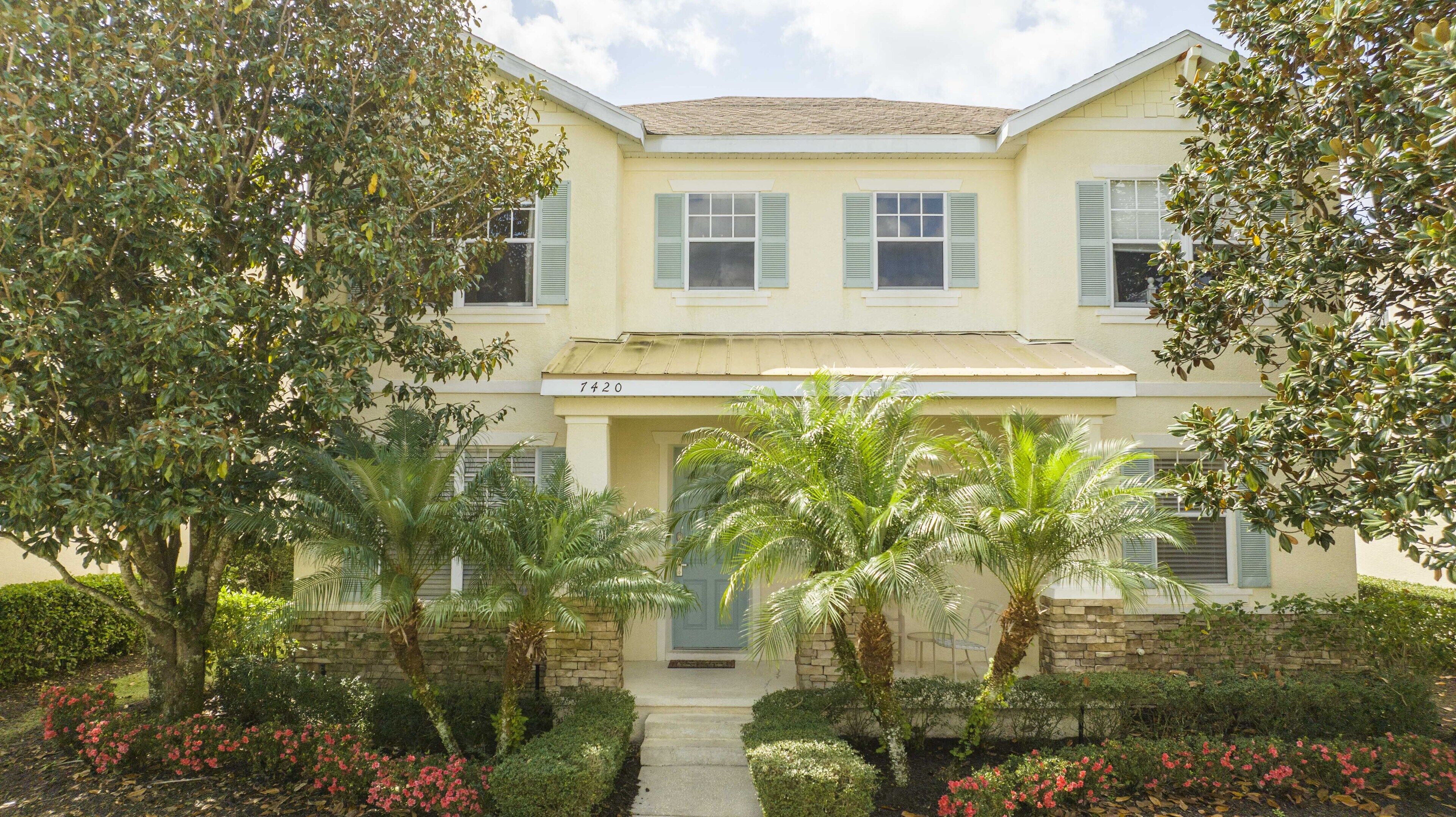 A two-story building with a stone facade, numbered 7420, featuring a central entrance with a door and a small porch area.