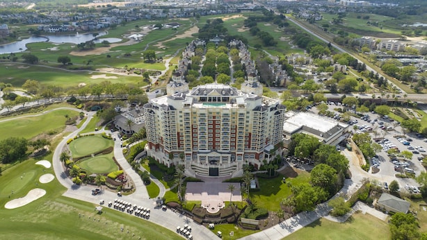 A large, multi-story hotel with a central courtyard, surrounded by well-maintained golf course and parking areas. - Stunning 5 Bd Home w/ Pool Close to Disney 7420 (Kissimmee)