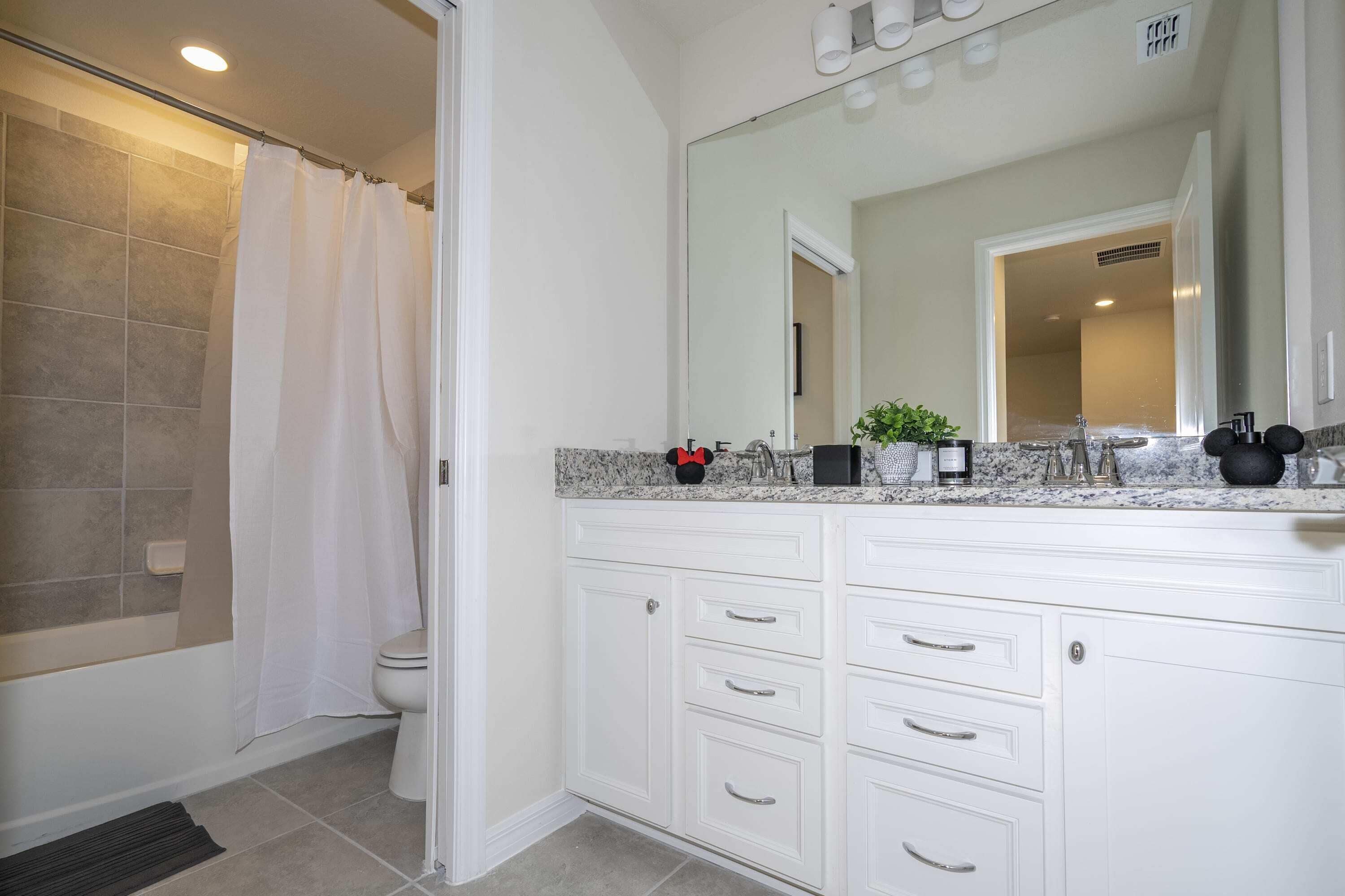Een badkamer met een douche, toilet en een wastafel met lades en een spiegel.