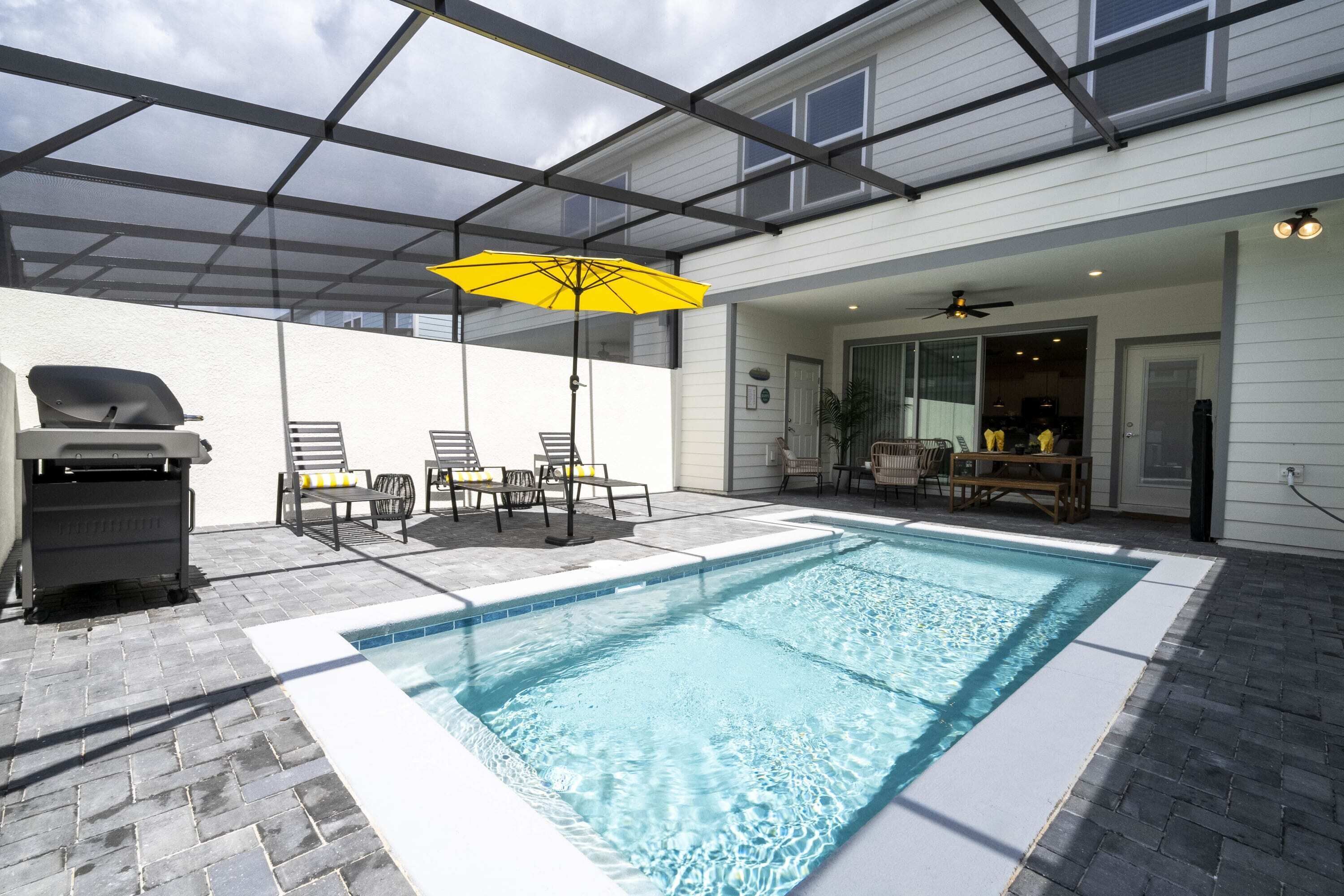 A backyard with a swimming pool, patio furniture, and a grill.