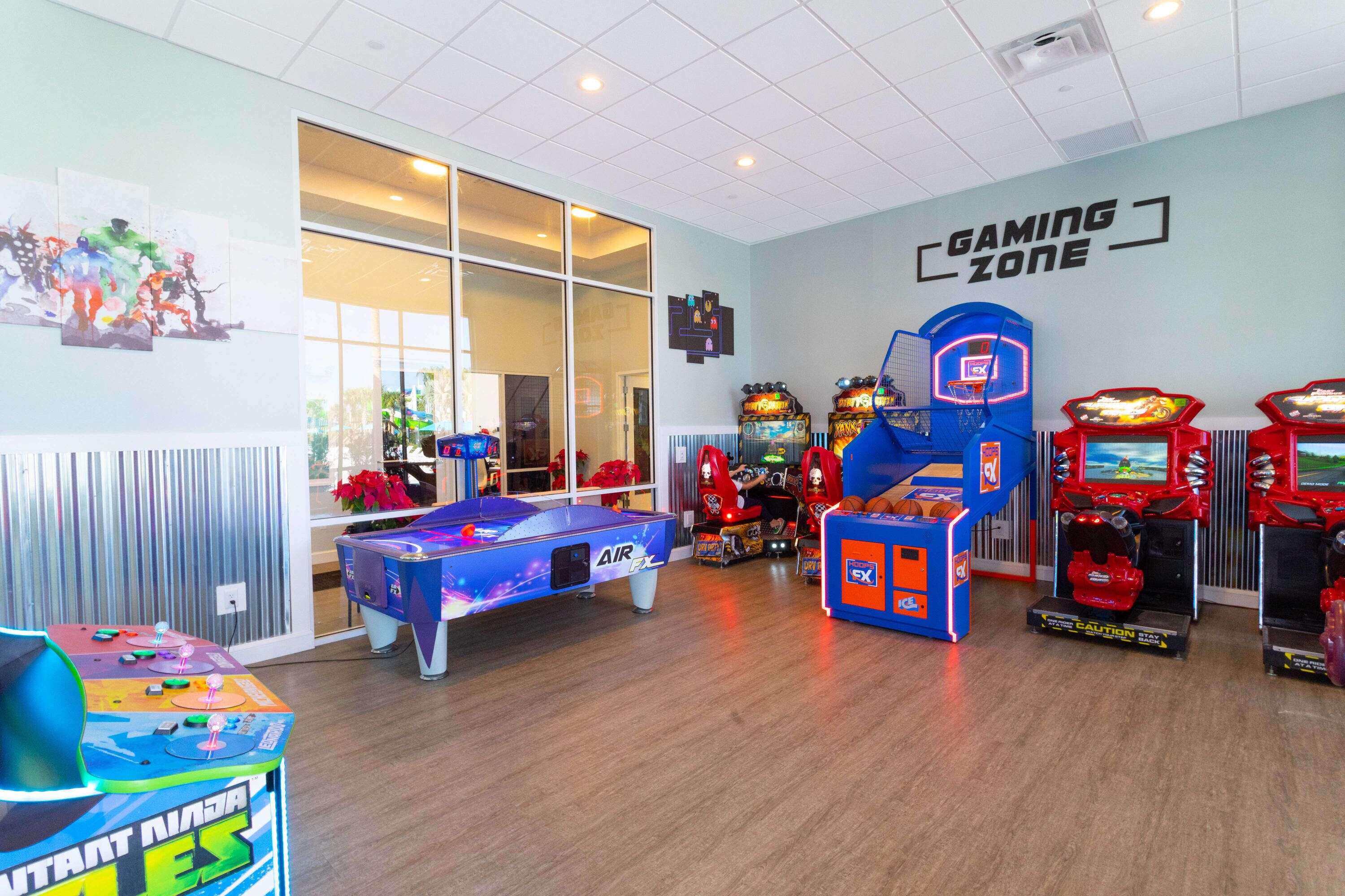 Een speelzone met diverse spelautomaten, een pooltafel en een basketbalspelautomaat.