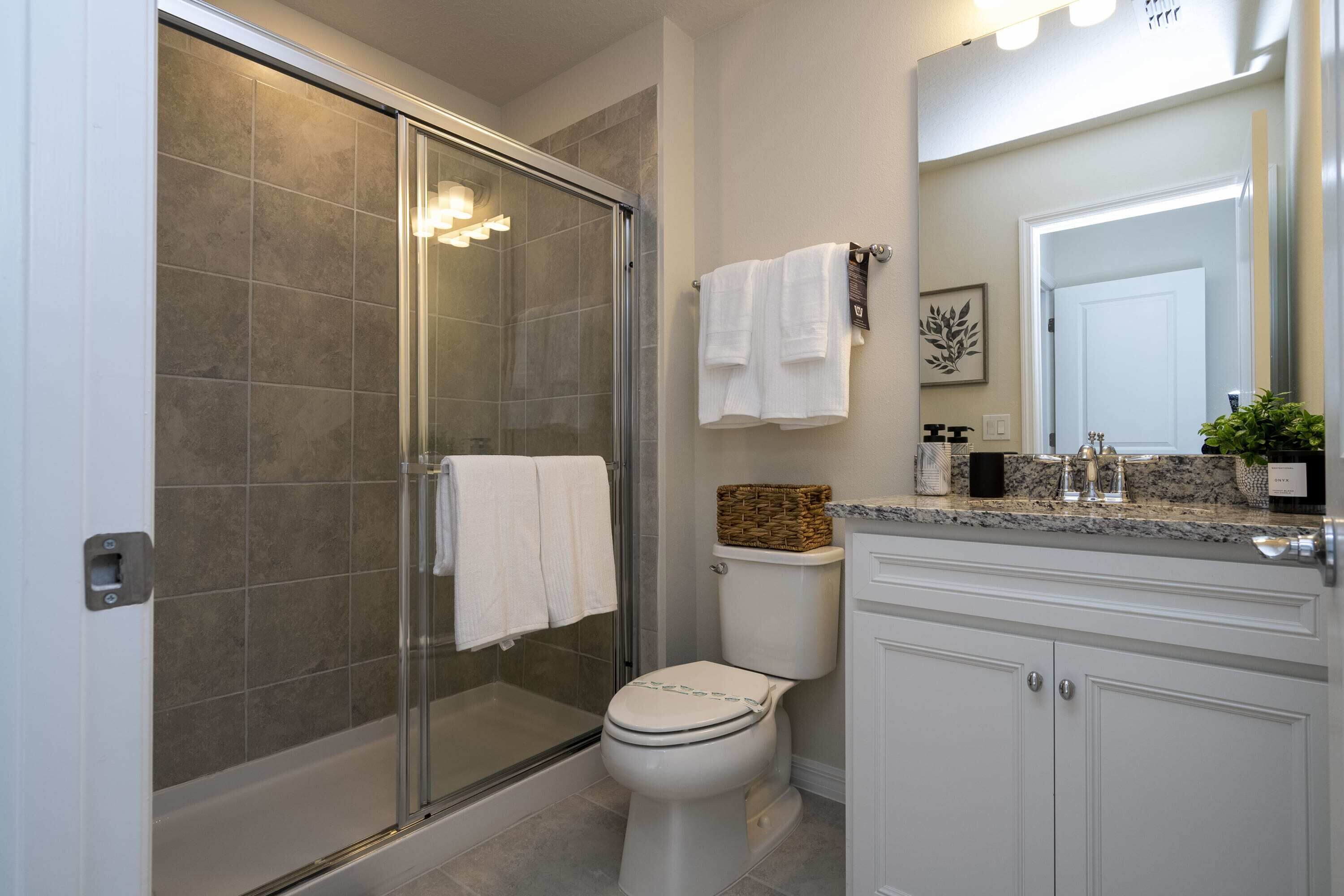 Un baño con ducha acristalada, inodoro y tocador con espejo.