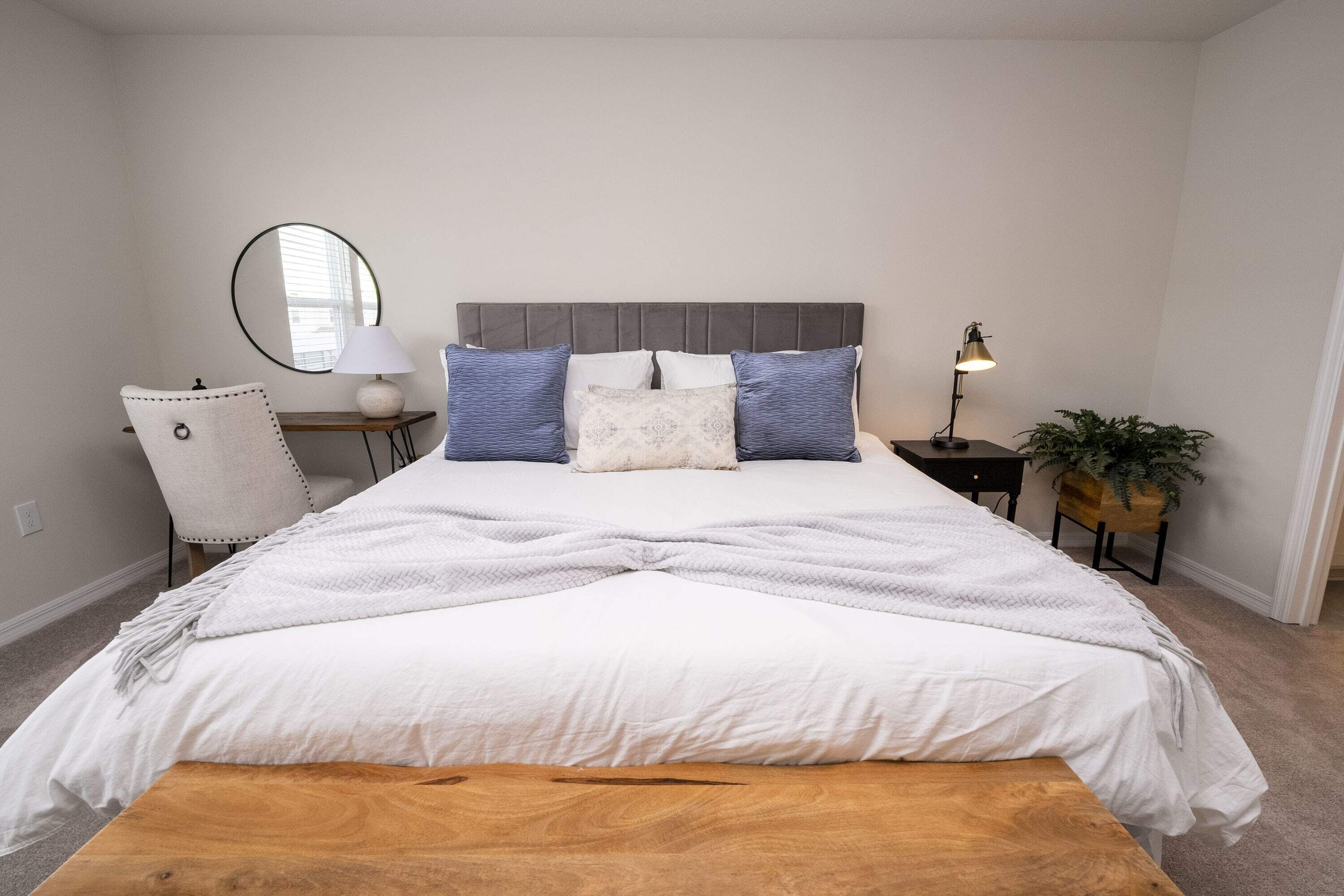 Ein Schlafzimmer mit Bett, Schreibtisch, Stuhl, Lampe und Pflanze.