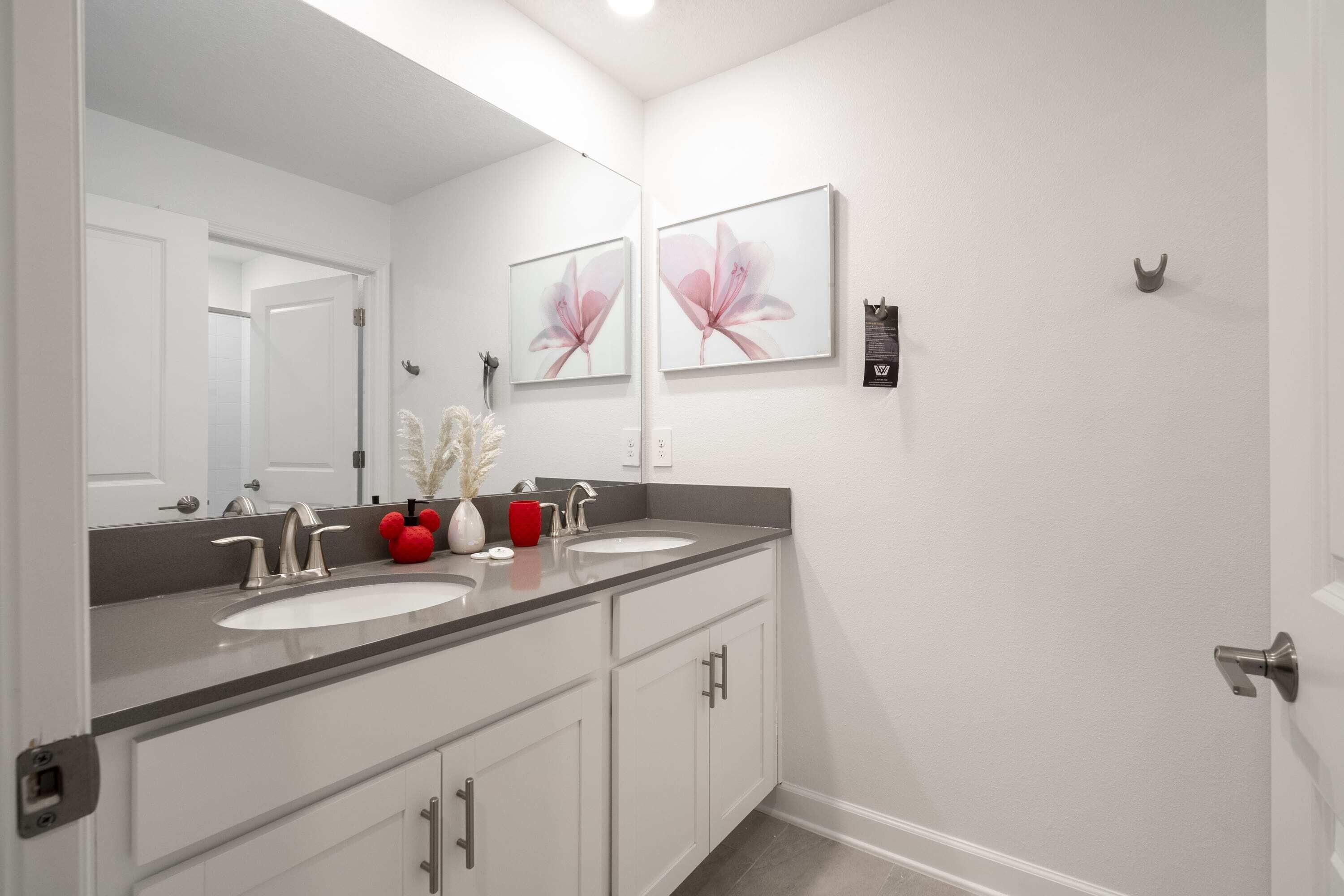 Un bagno con due lavandini, uno specchio grande e opere d'arte appese alle pareti.