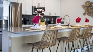 A modern kitchen with white cabinets, stainless steel appliances, and a central island with bar-style seating. - WonderFull 4Bd with Pool at Champions Gate 1174 (Davenport)