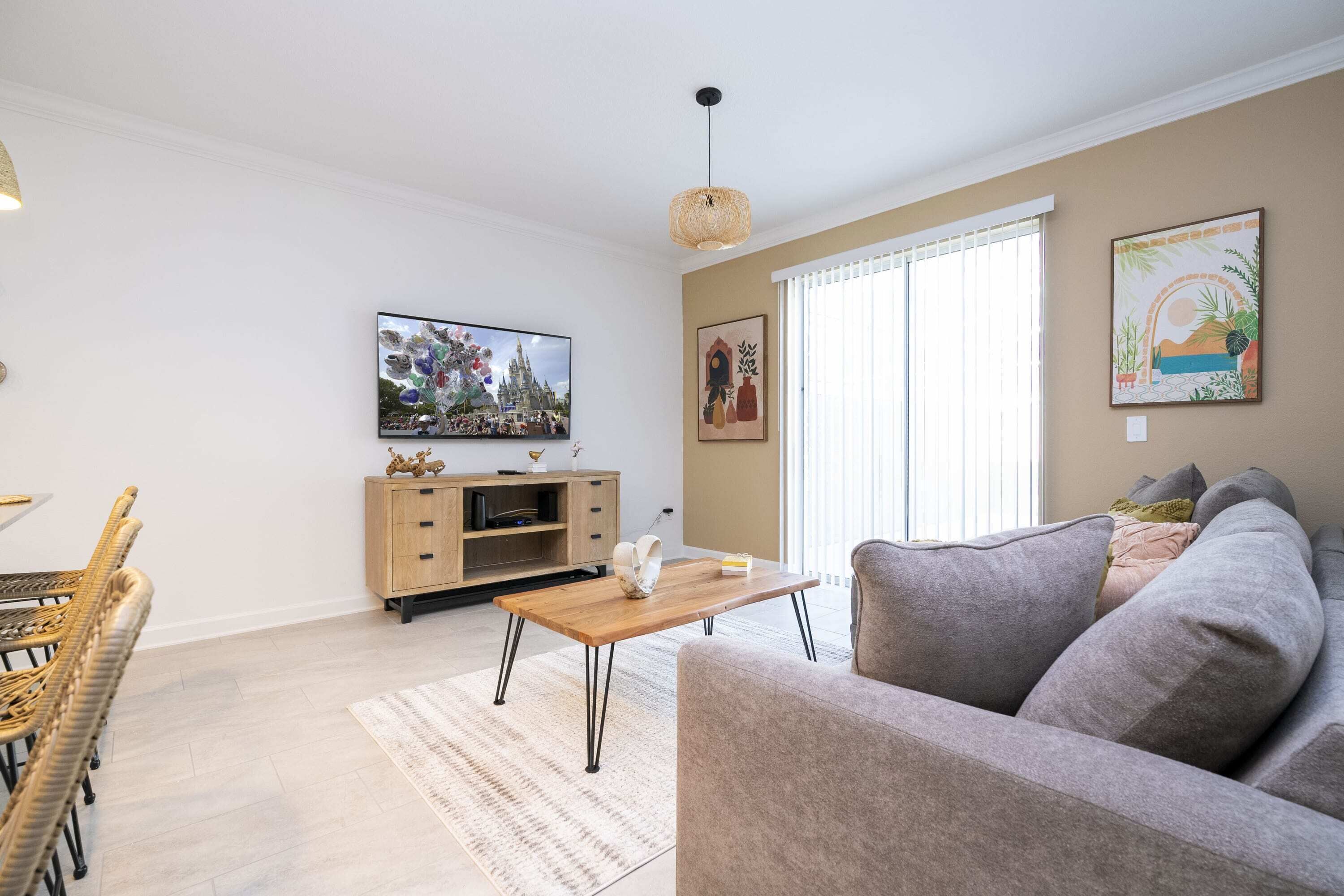 A living room with a sofa, a wooden coffee table, a TV, and a dining area with wicker chairs.