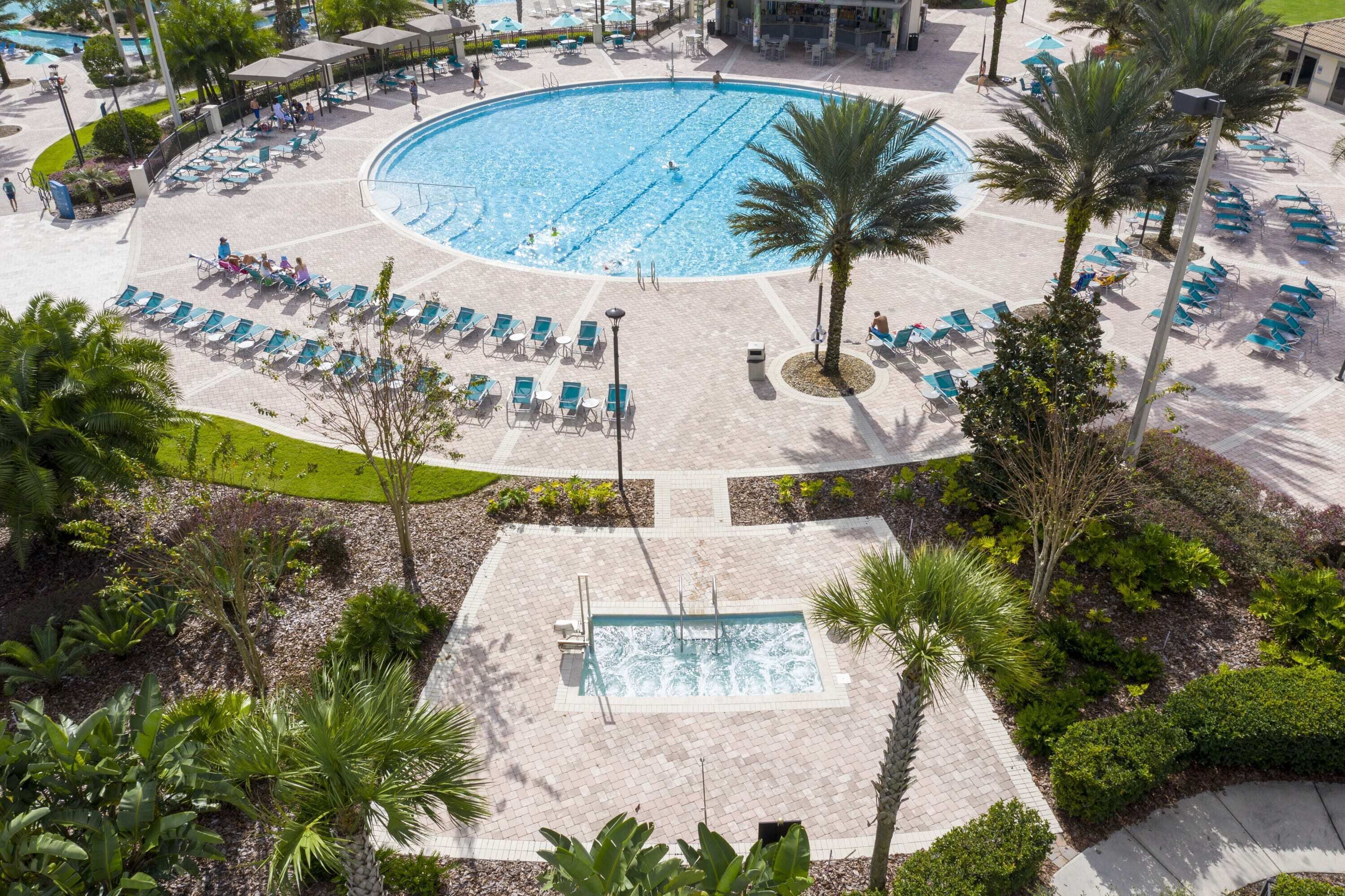 Une grande piscine extérieure entourée de chaises longues et de palmiers.
