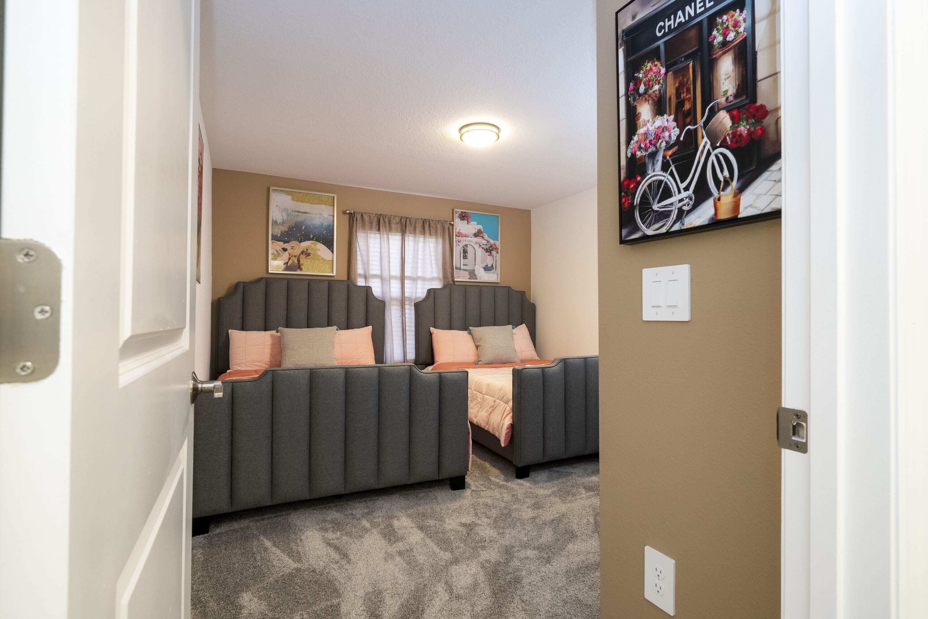 A room with two grey sofas, beige walls, a chandelier, and a poster of a bicycle.