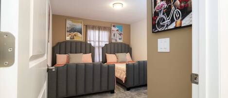 A room with two grey sofas, beige walls, a chandelier, and a poster of a bicycle.