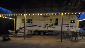 Una caravana estacionada amb un porxo cobert, mobiliari d'exterior i llums de garlandes.