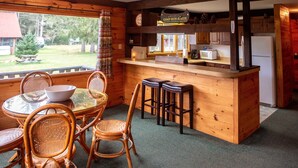 A wooden cabin interior with a dining area, bar, and kitchen. - Sweet Chalet by the Lake! (Stony Creek)