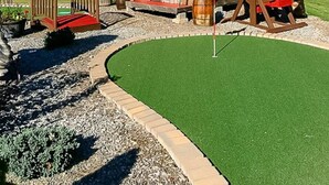 A rustic play area with a wooden playhouse, a large wooden merry-go-round, and a small slide. - Sweet Chalet by the Lake! (Stony Creek)