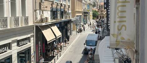 Une vue de rue avec un magasin Sephora, une banderole pour « Simply Green » sur un immeuble et un tramway en arrière-plan.