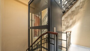 A modern interior with a glass staircase, metal railings, and a tiled floor.