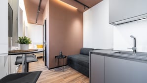 A compact kitchen with a grey countertop, a sink, and a small table with a plant.