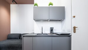 A modern kitchen with grey cabinetry, a built-in stove, and a coffee maker.