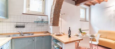 Een koelkast, een oven, een kookplaat, kookgerei, borden en bestek