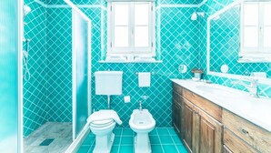 Et badeværelse med bruser, toilet, bidet og vask.