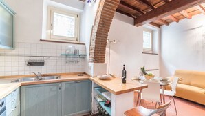 Et køkken med træloft, vask, vindue samt spiseplads med bord og stole.