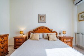 Une chambre à coucher avec un grand lit, deux tables de chevet, une tête de lit en bois et un tableau encadré au mur.
