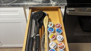 Une cuisine équipée d’une machine à café, d’un tiroir contenant des ustensiles et des produits McCain, et d’une cuisinière.