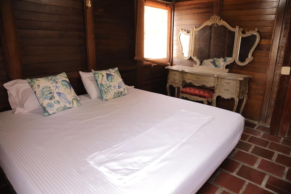 Una habitación de madera con una cama grande, un aparador y un espejo.