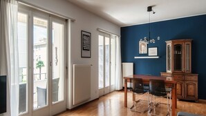 A dining area with a wooden table and chairs, a radiator, and a cabinet against a blue wall. - Apartment 5 minutes from Locarno Centro (Victoria Apartment) (Solduno)