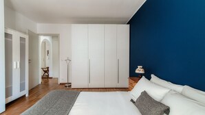 A bedroom with a large bed, white wardrobe, and a blue accent wall. - Apartment 5 minutes from Locarno Centro (Victoria Apartment) (Solduno)