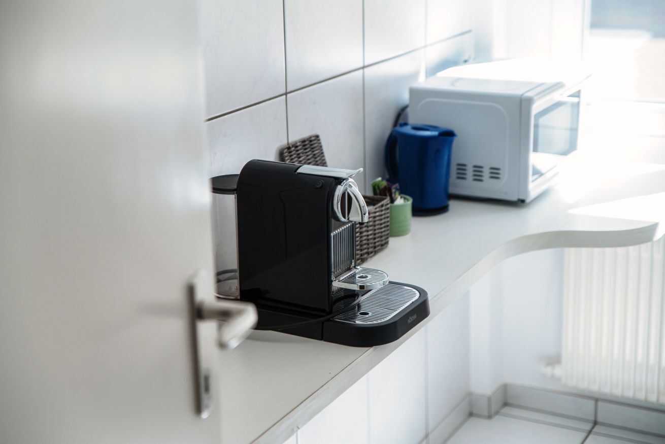 A kitchen with a coffee machine, a microwave, and a basket on the counter.