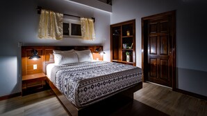 A bedroom with a wooden bed, a nightstand, a bedside lamp, a wardrobe, and a window with curtains.