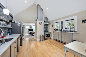 Une cuisine moderne avec un mur de crédence en pierre, une grande cuisinière et un coin repas comprenant une table et des chaises.